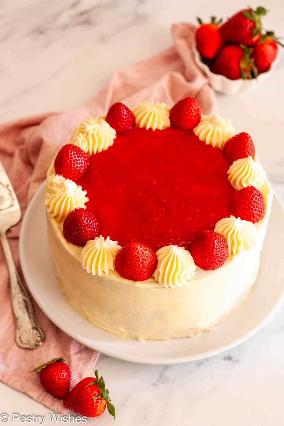 Chocolate strawberry layer cake with smooth buttercream frosting and piped swirls topped with fresh strawberries.