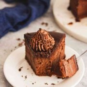 Close-up of chocolate ganache cheesecake slice with whipped cream topping.