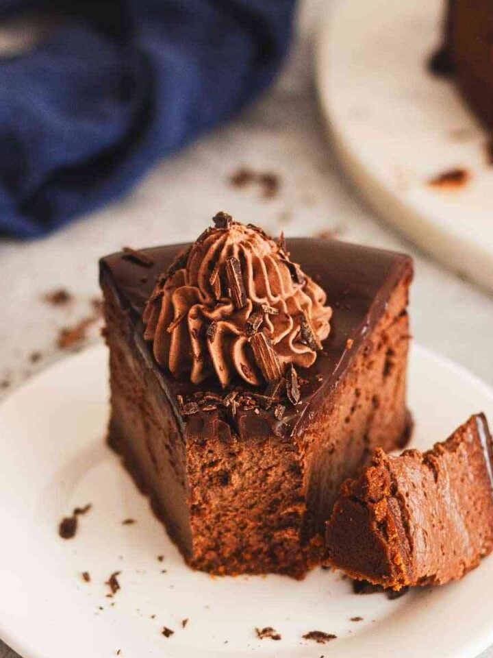 Close-up of chocolate ganache cheesecake slice with whipped cream topping.