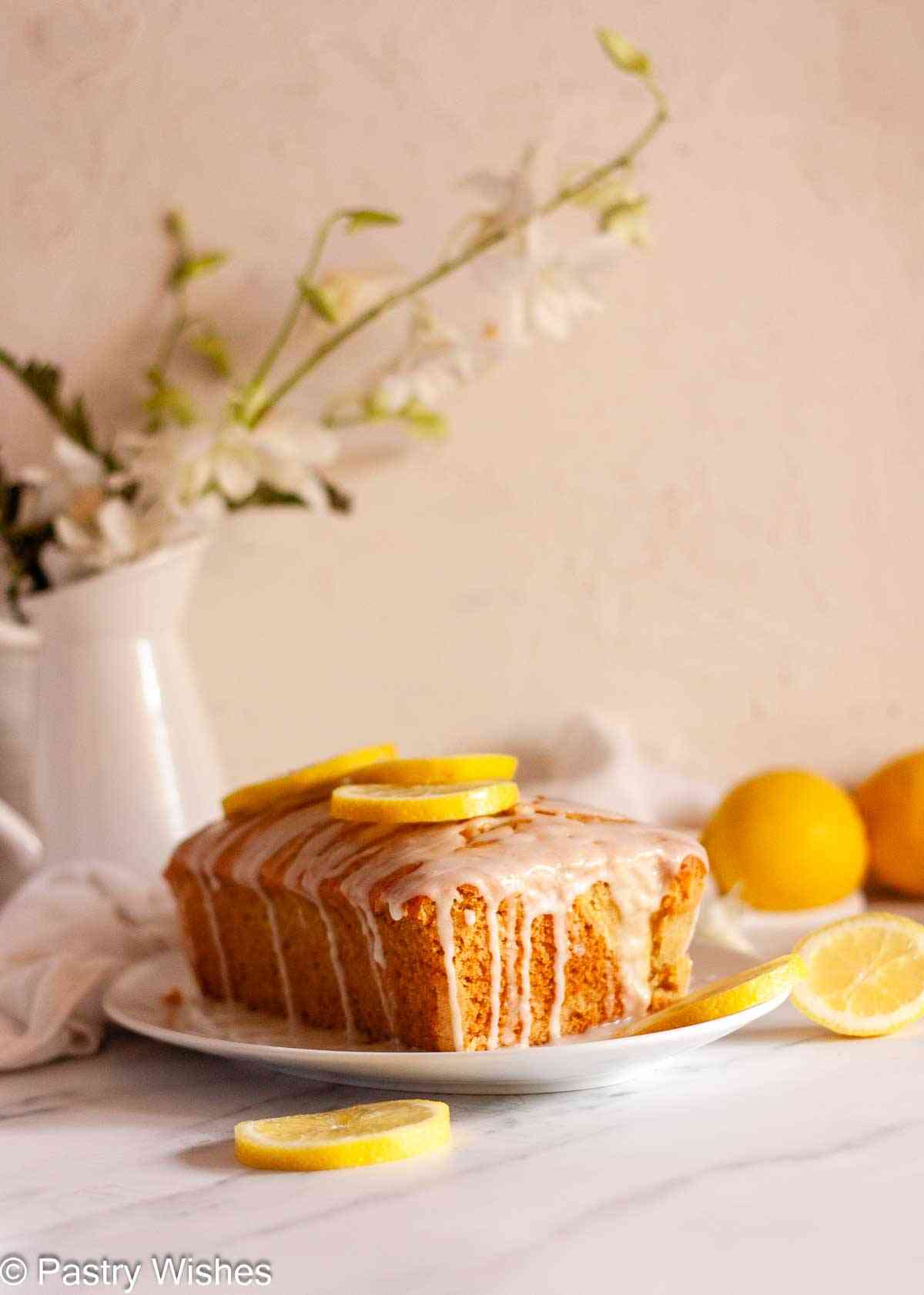 Eggless lemon loaf cake with lemon glaze and fresh lemon slices on top.