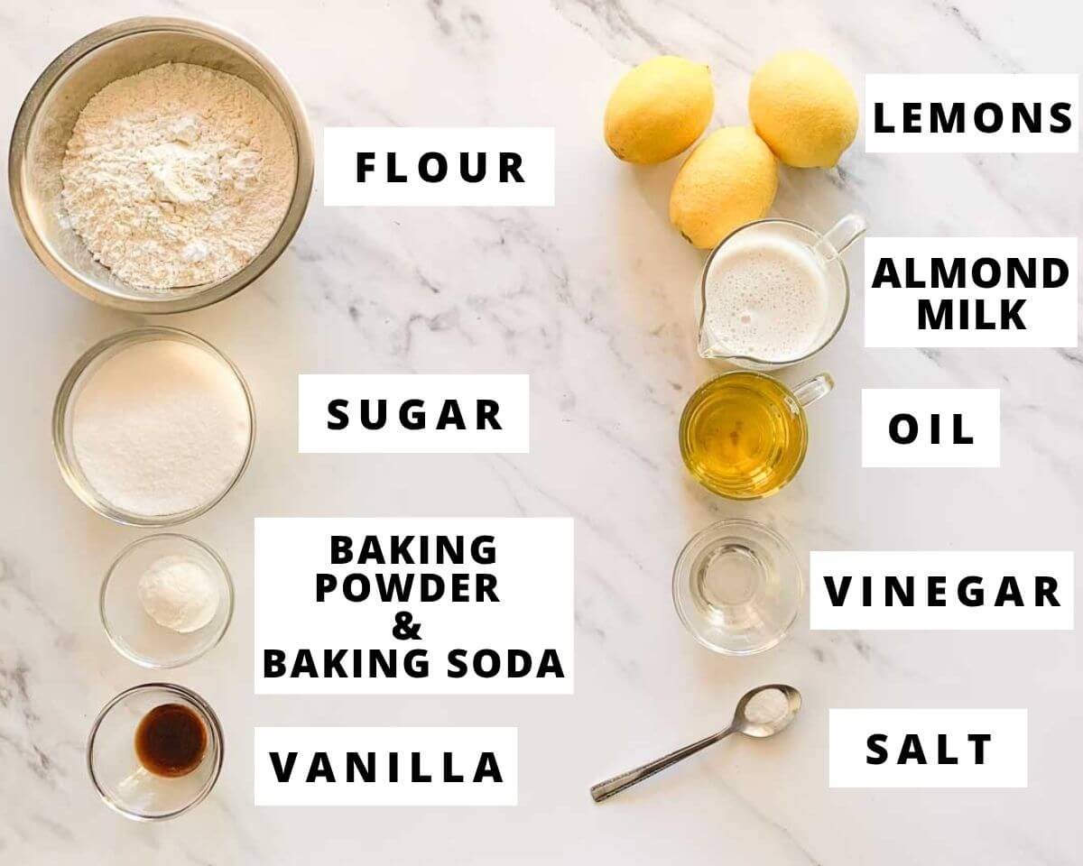 Ingredients for eggless lemon cake including flour, lemons, almond milk, oil, sugar, vinegar, vanilla, baking powder, baking soda, and salt.