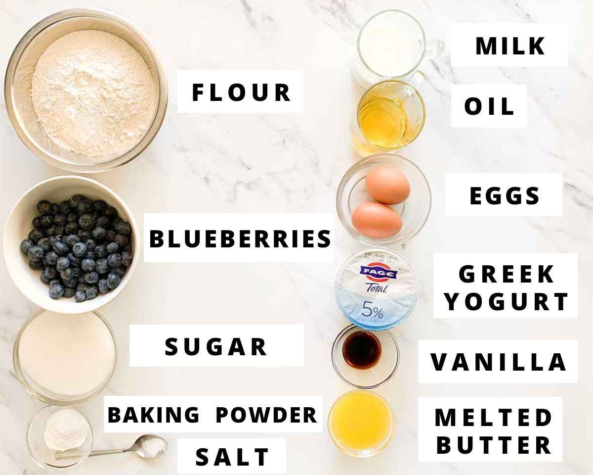 Ingredients for Greek yogurt blueberry muffins labeled on a marble background.