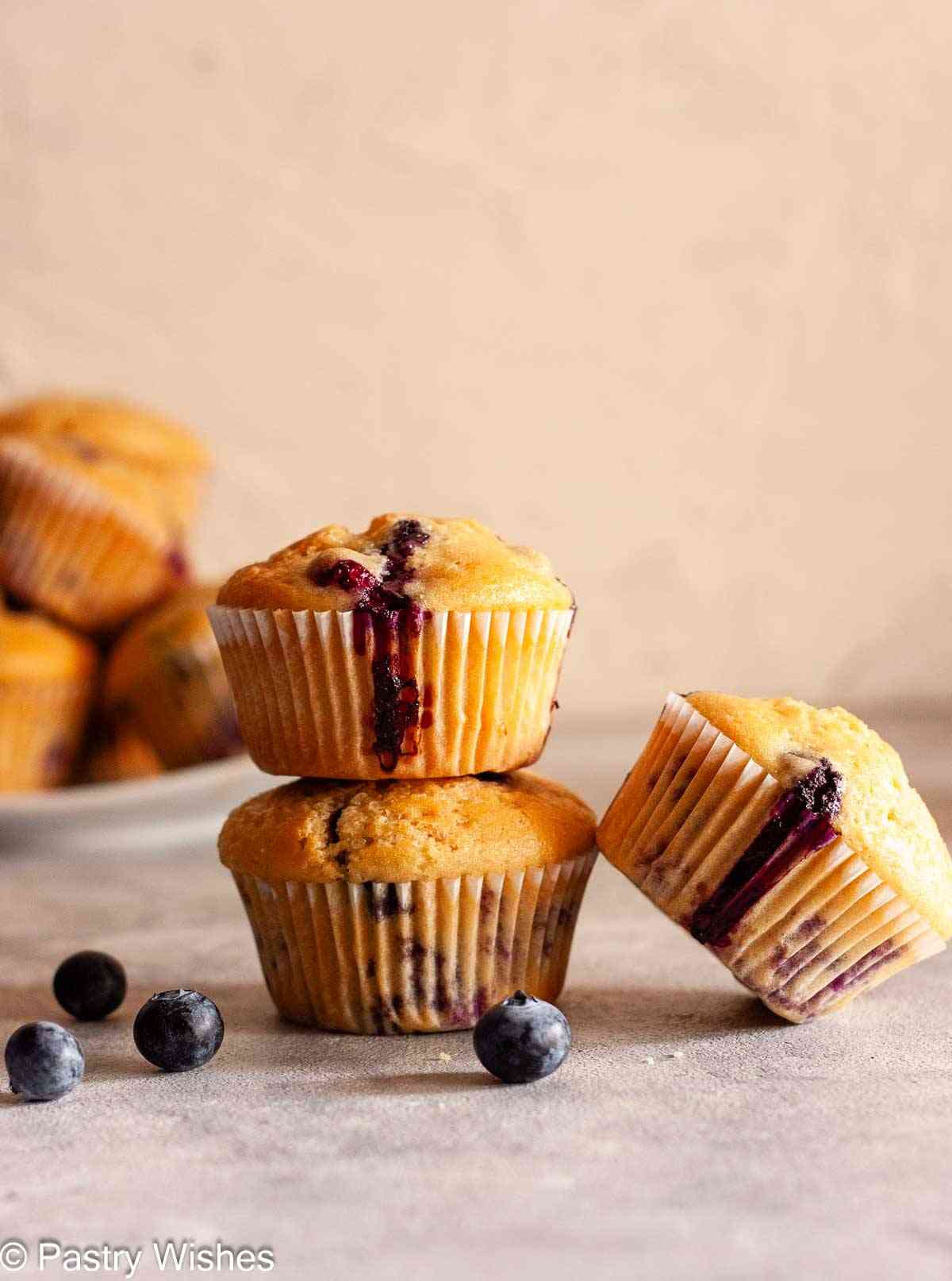 Stacked dairy-free blueberry muffins with golden tops and blueberry filling.
