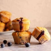 Dairy-free blueberry muffins with golden tops, juicy blueberries, and fresh blueberries on the side.