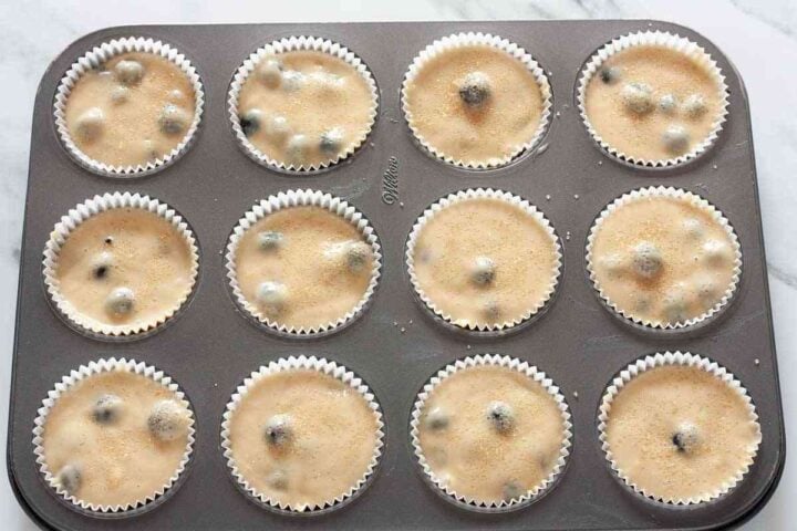 Step 6: Dairy-free blueberry muffin batter divided into a lined muffin pan before baking.