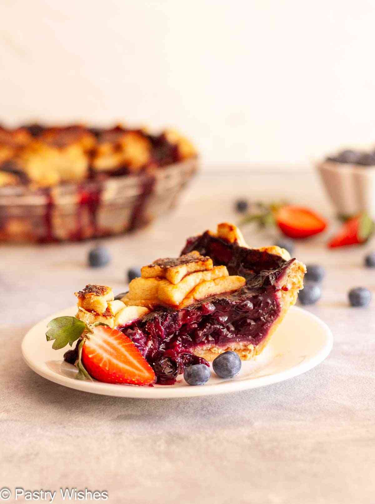 Slice of strawberry blueberry pie with juicy berry filling and star-shaped crust topping.