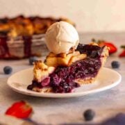 Homemade strawberry blueberry pie served with a scoop of vanilla ice cream.