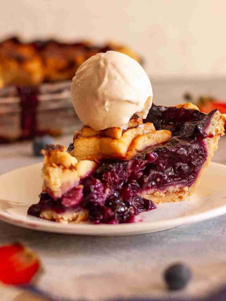 Homemade strawberry blueberry pie served with a scoop of vanilla ice cream.
