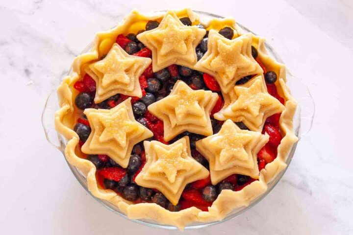 Unbaked strawberry blueberry pie topped with decorative star-shaped crust pieces.