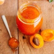 Homemade apricot jam without pectin in a glass jar with fresh apricots and a spoonful of jam.
