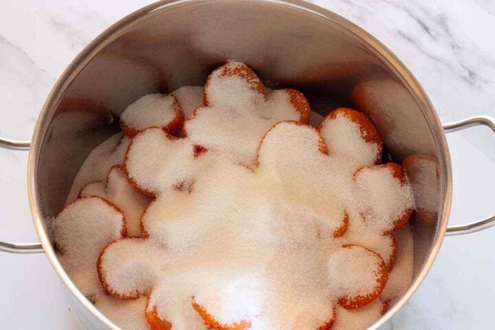 Step 1: Fresh apricots layered with sugar in a large pot for homemade apricot jam.