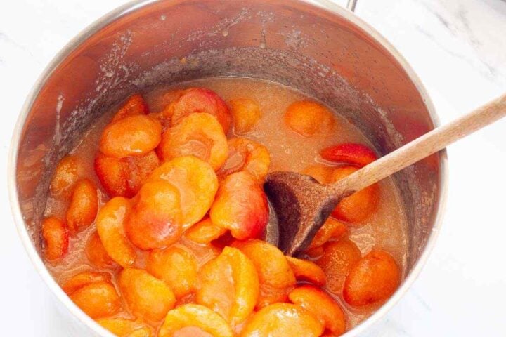 Step 2: Apricots cooking with sugar and lemon juice in a pot until they release their juices.