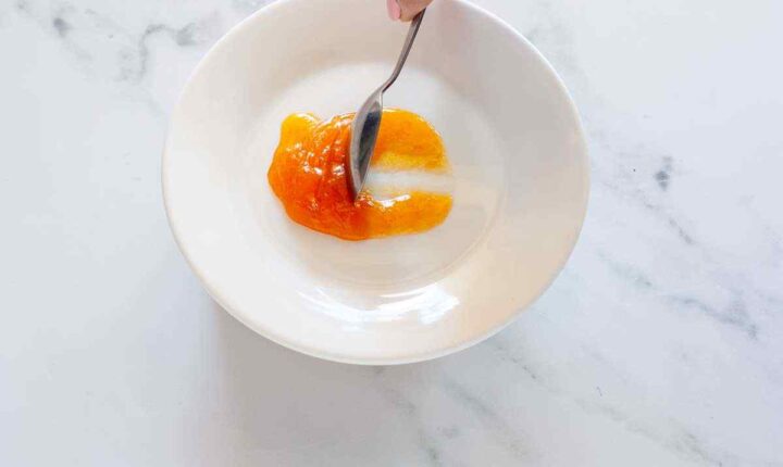 Step 5: Testing apricot jam on a chilled plate by drawing a line through the jam with a spoon.