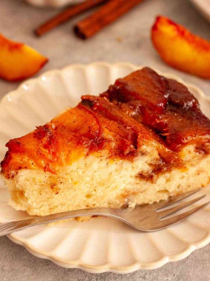 Close-up of a slice of caramel peach upside-down cake with a soft crumb and glossy peach topping.