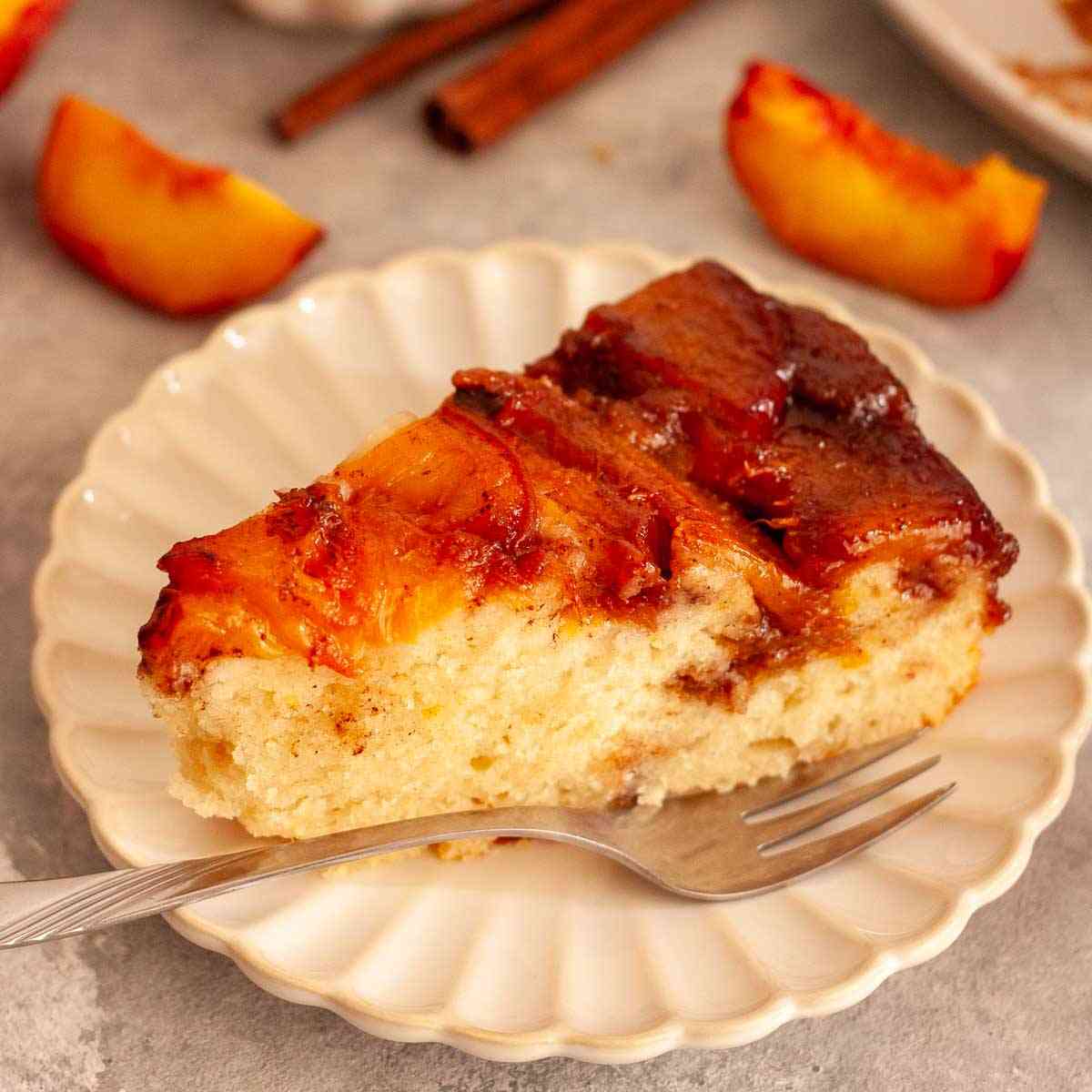 Close-up of a slice of caramel peach upside-down cake with a soft crumb and glossy peach topping.
