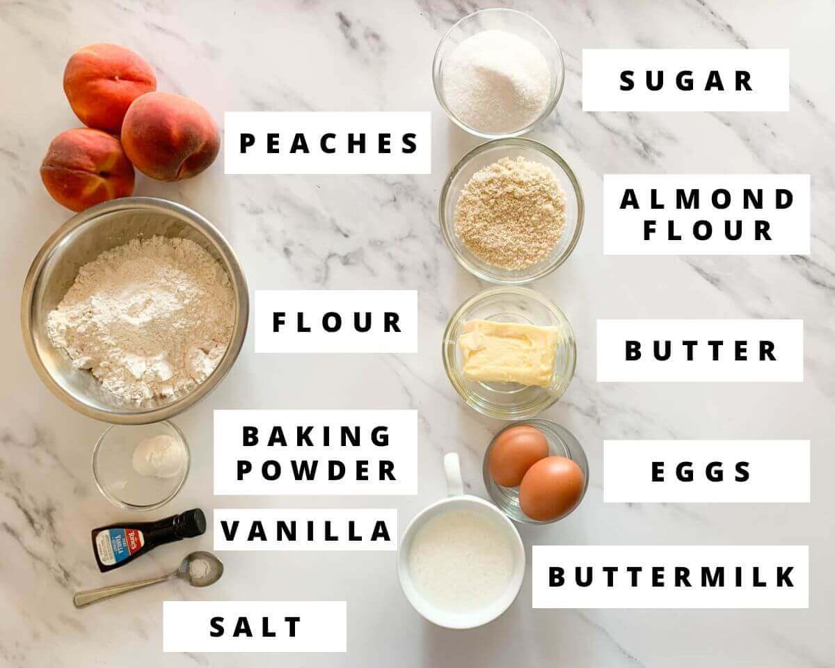 Labeled ingredients for caramel peach upside-down cake, including fresh peaches, flour, almond flour, butter, eggs, sugar, and buttermilk.