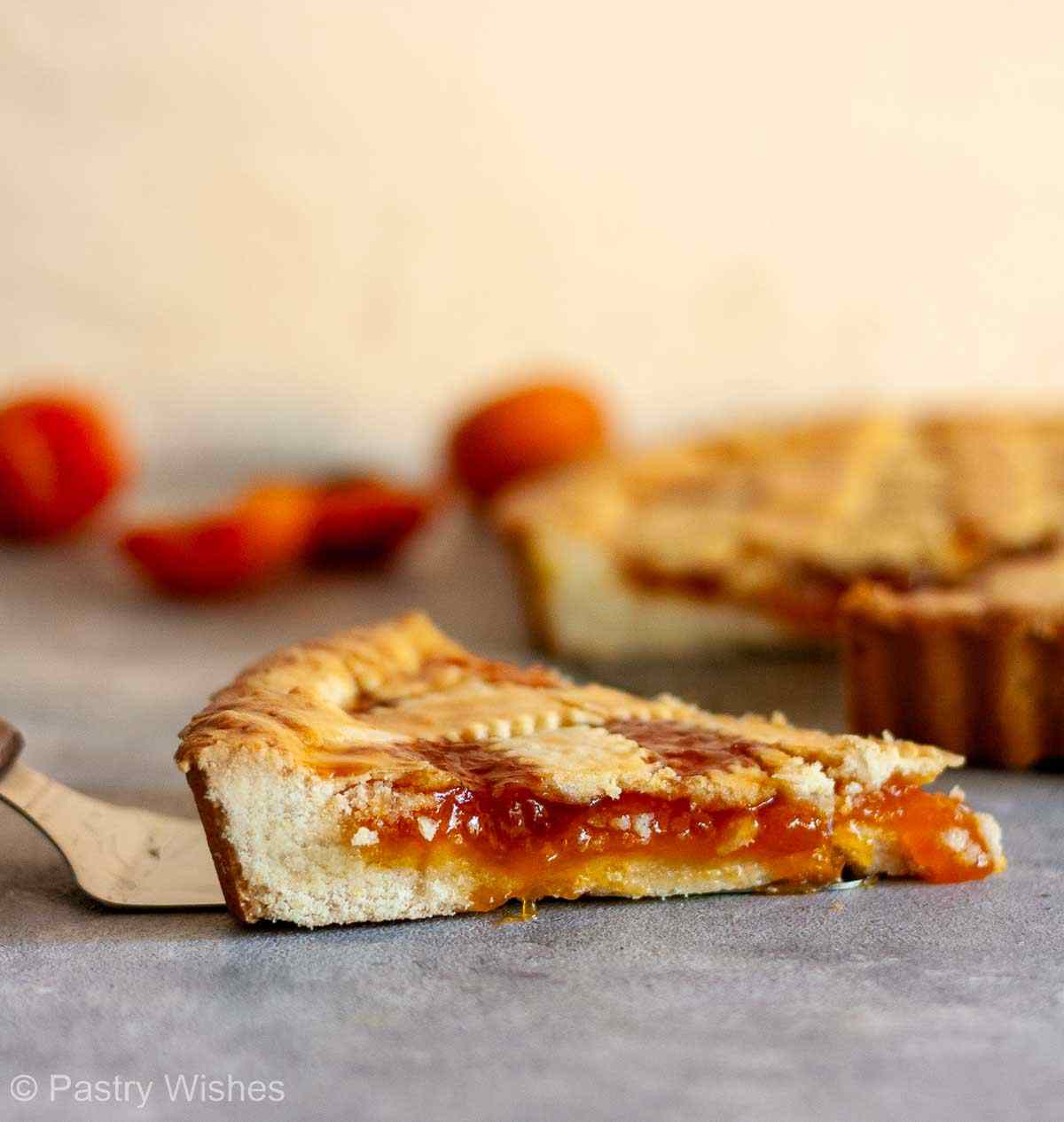 Close-up of pasta flora slice showing thick cookie-like crust and apricot jam filling.
