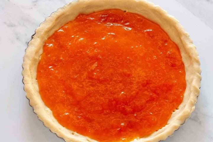 Apricot jam spread evenly over the chilled pasta flora tart shell.