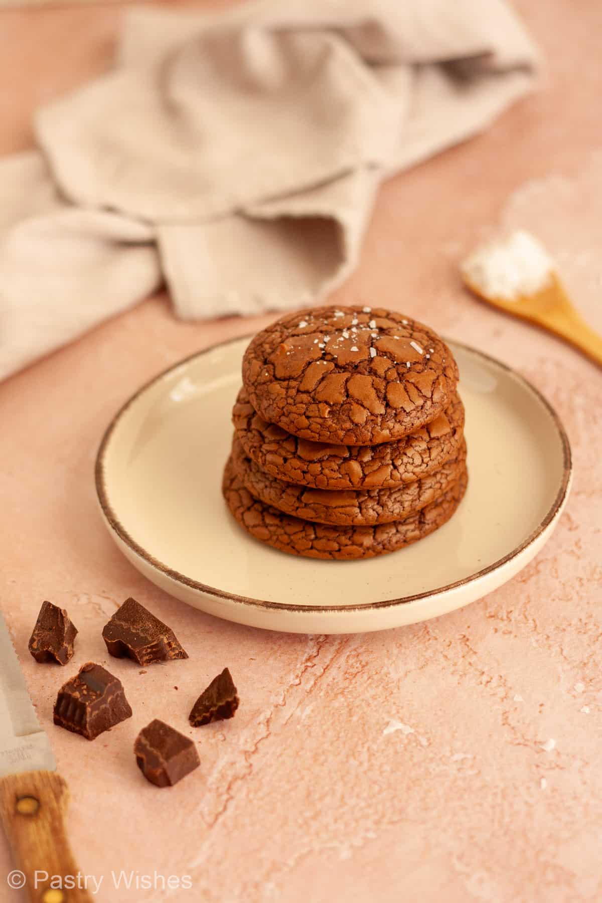 Stack of fudgy brownie crinkle cookies with shiny cracked tops on a plate.