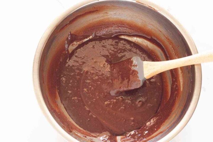 Thick chocolate brownie cookie batter mixed together with a rubber spatula.