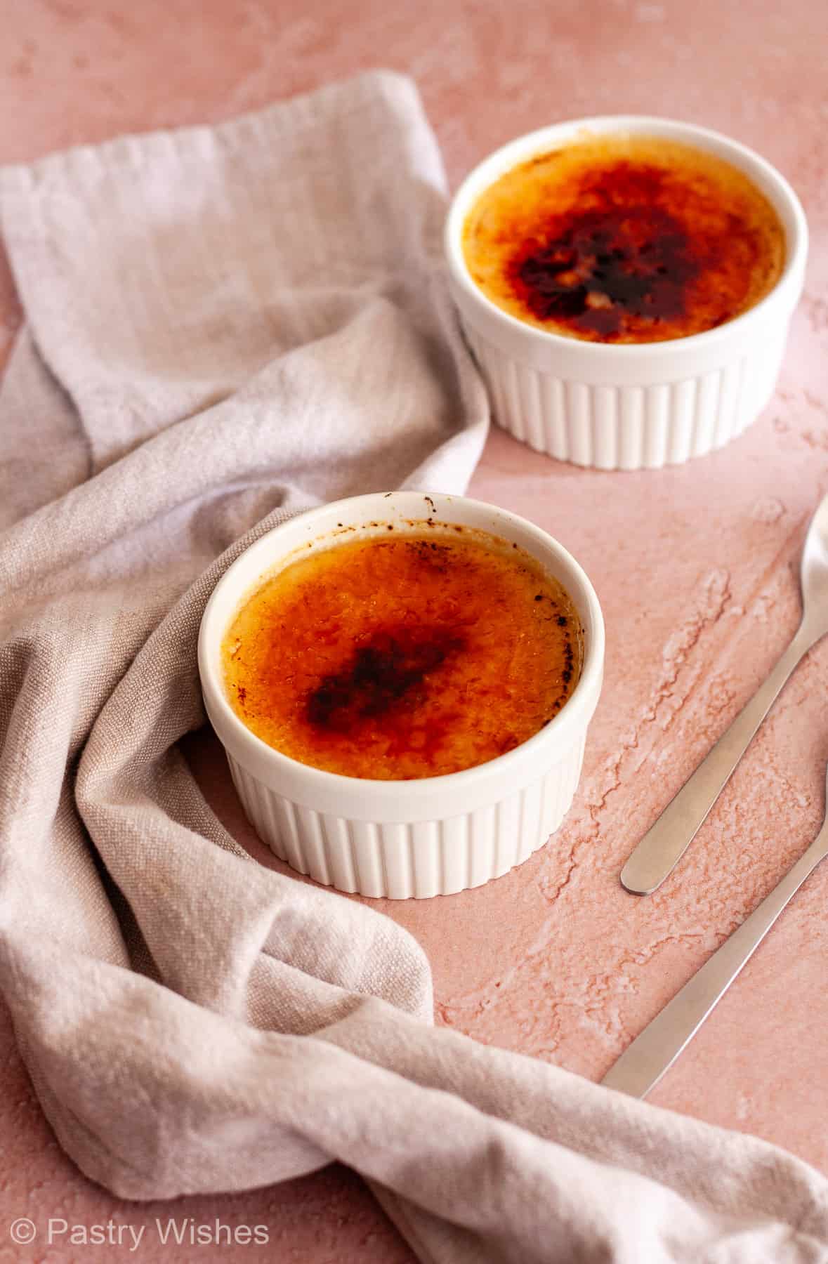 Two no-bake crème brûlées with caramelized sugar tops in white ramekins.