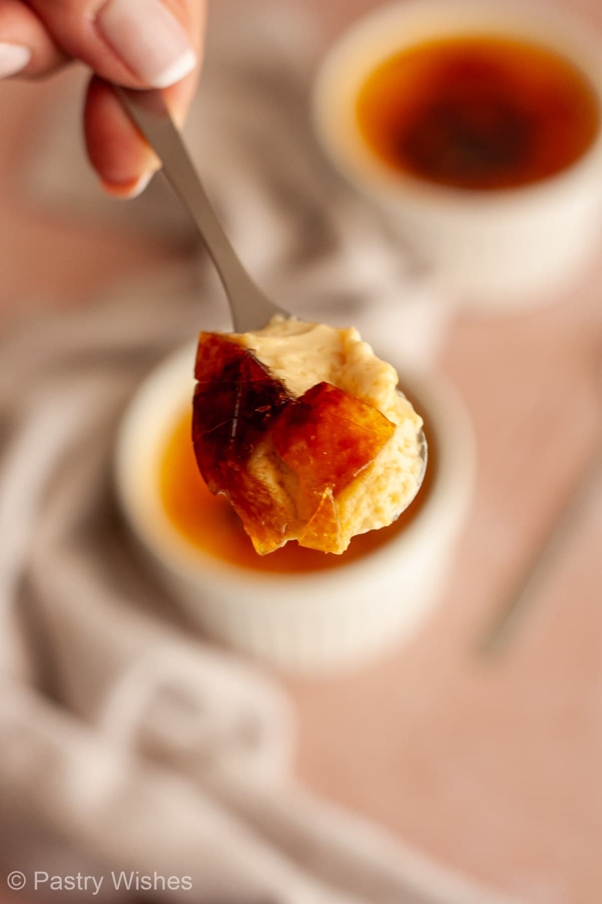 Close-up of a spoonful of crème brûlée with creamy custard and shards of caramelized sugar.