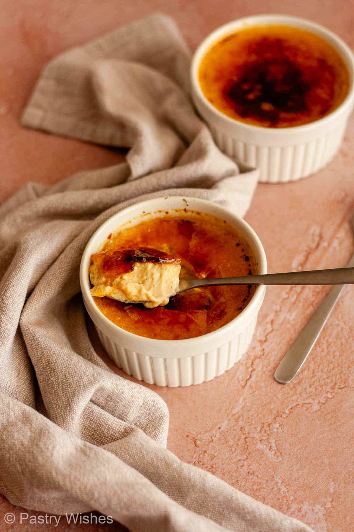 Spoon lifting crème brûlée to reveal the creamy vanilla custard beneath the sugar crust.