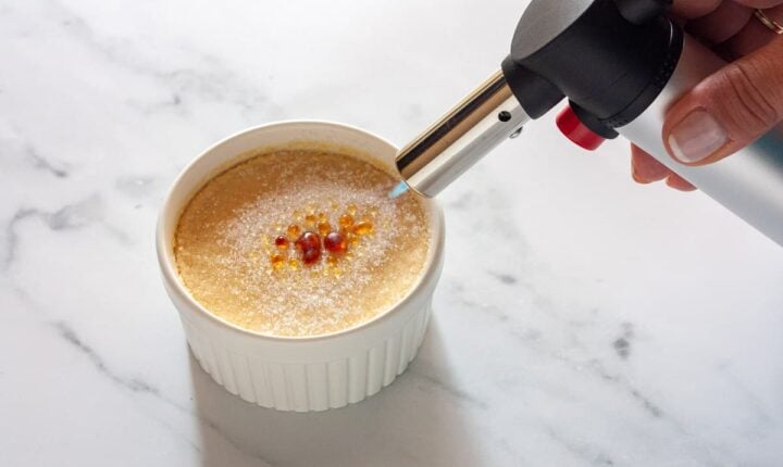 Caramelizing the sugar topping on crème brûlée with a kitchen torch.