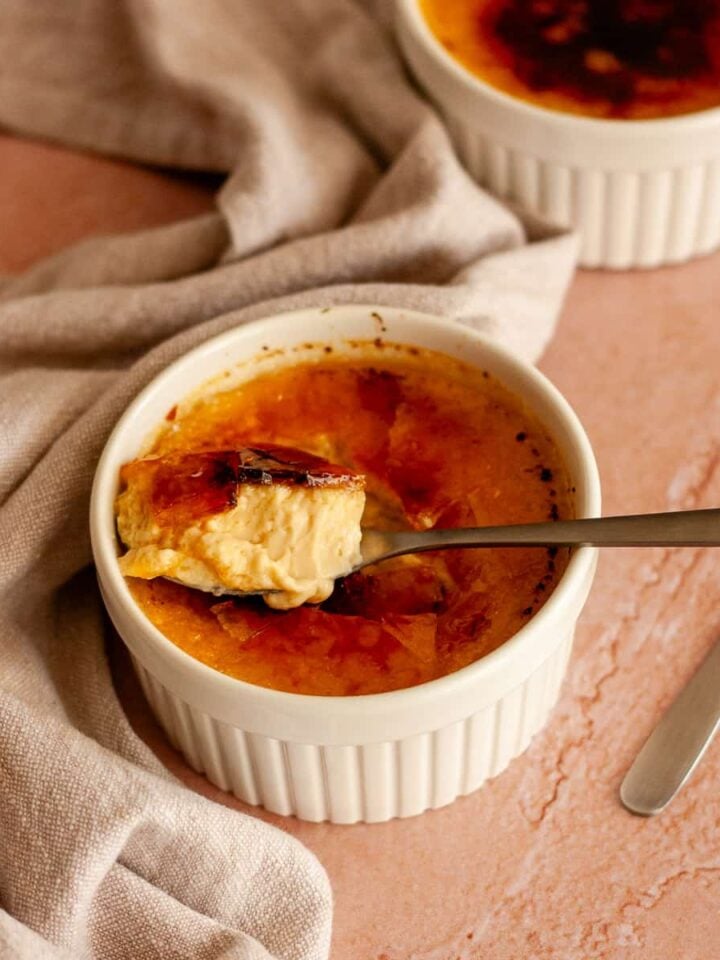 No-bake crème brûlée in a white ramekin with a spoonful of custard and caramelized sugar.