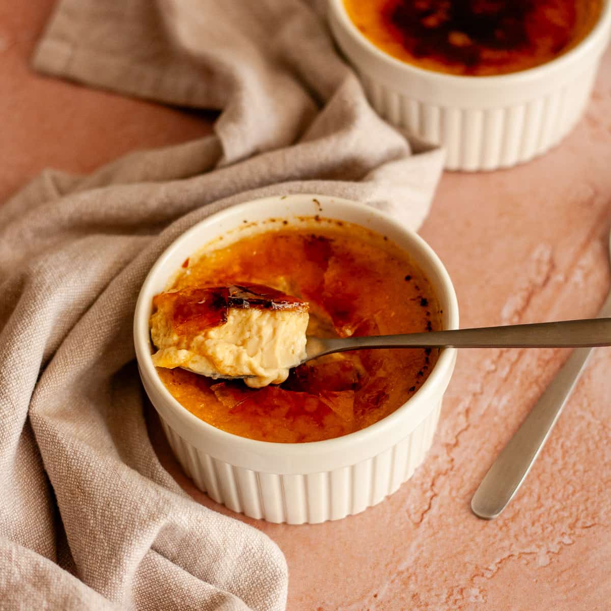No-bake crème brûlée in a white ramekin with a spoonful of custard and caramelized sugar.